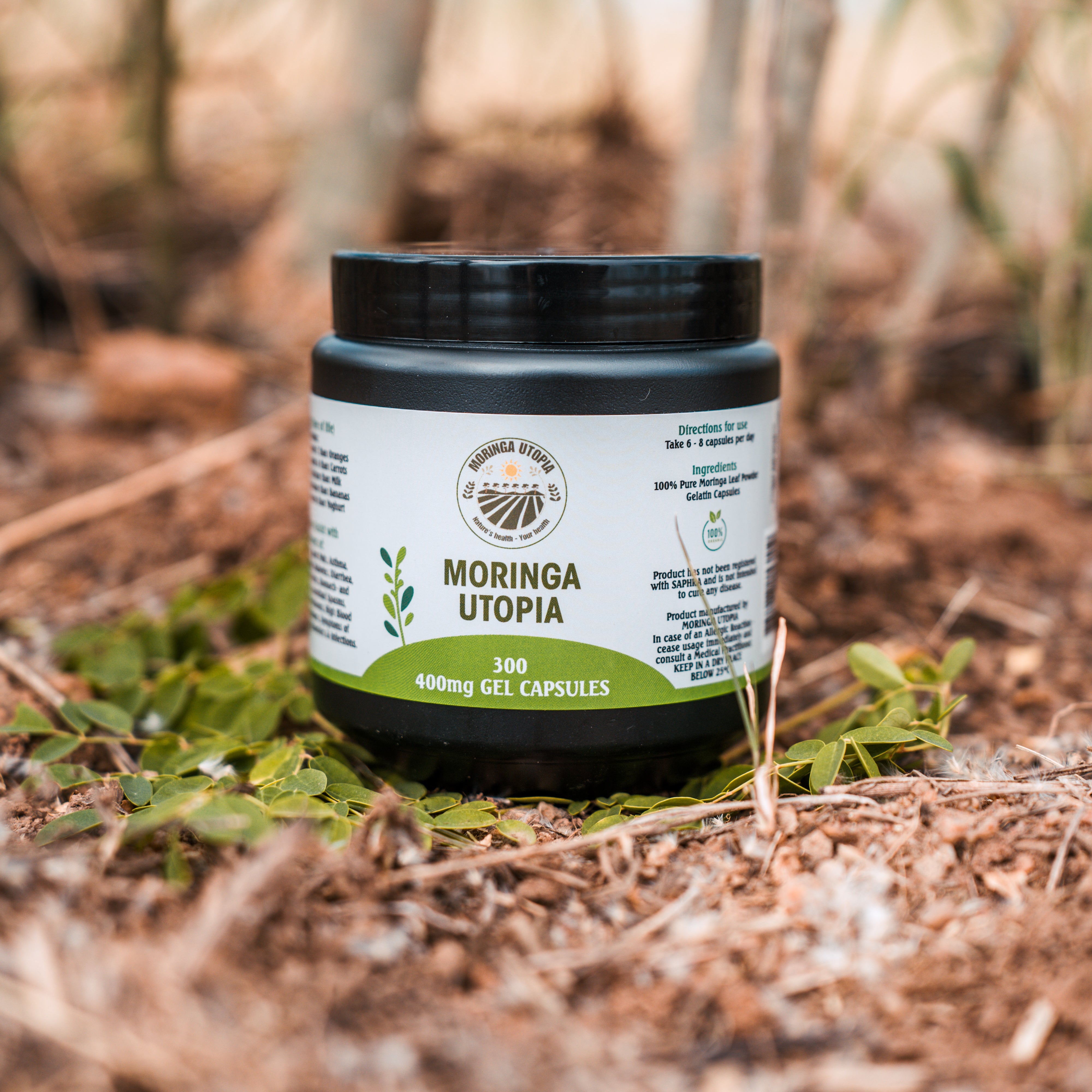 Moringa supplement container labeled 'Moringa Utopia' on a natural background with plants.