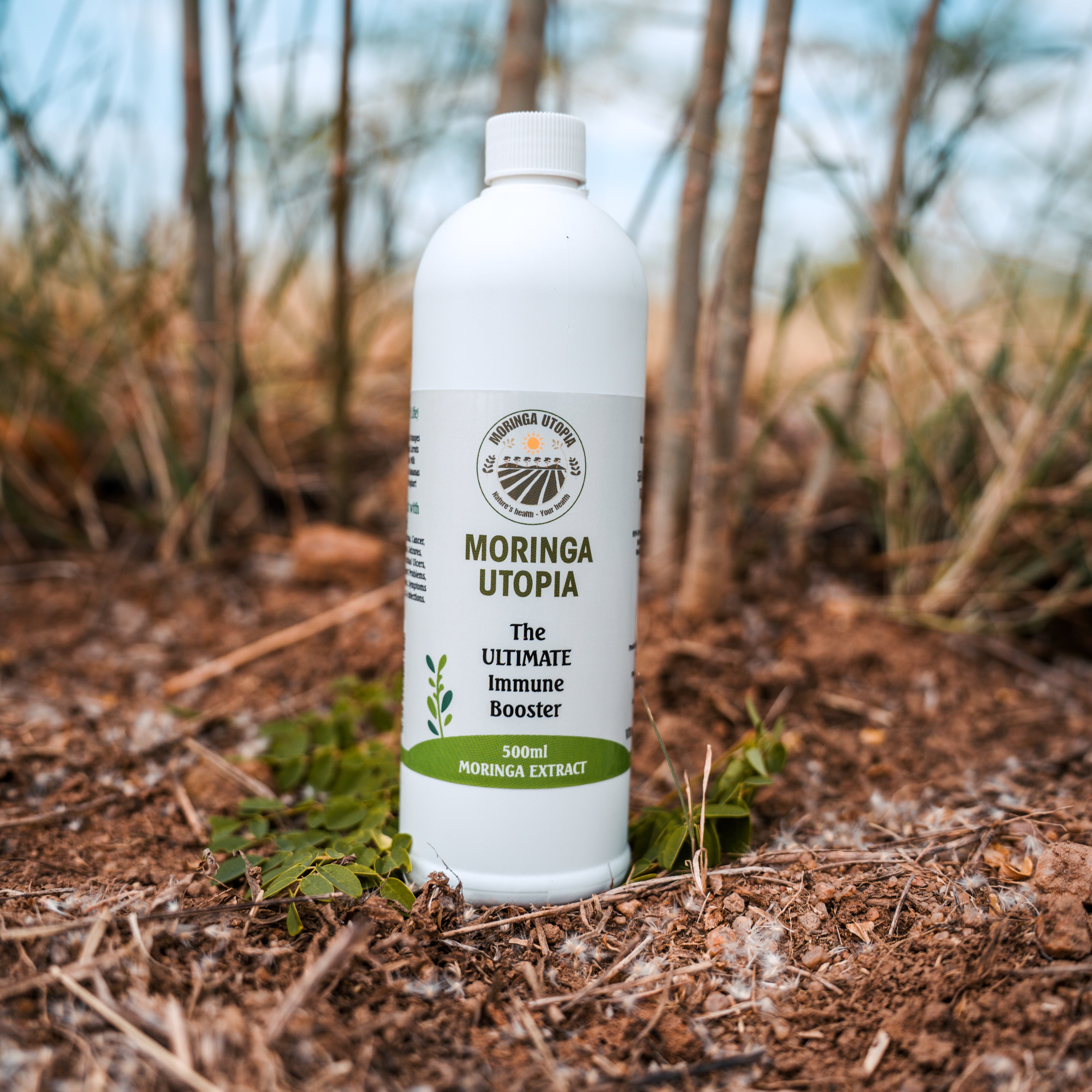 Moringa Utopia bottle on a natural background with trees and sky.